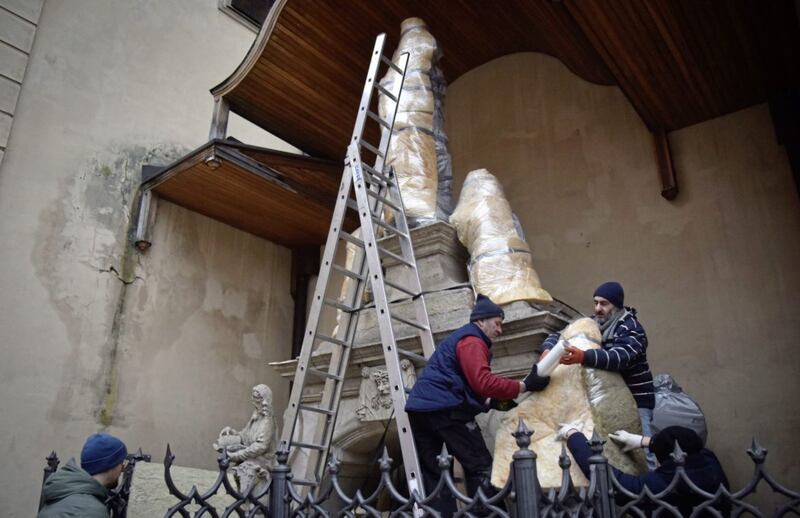 Workers wrap protective materials around a statue in Lviv, western Ukraine, where in an attempt to preserve ancient sculptures and stained glass windows in churches from bombs, they are packing them in special cocoons to protect them. Stained glass windows in churches have been covered with chipboard. Picture by AP Photo/Pavlo Palamarchuk. 