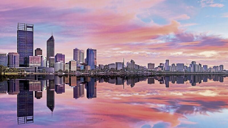 still reflection of Perth Western Australian capital at sunrise in calm waters of Swan River. Horizontal panorama with pink clouds and blue sky.