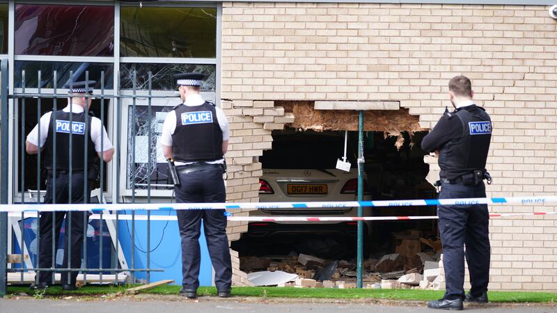 Police officers stand beside the debris and damage to the Beacon Church of England Primary School