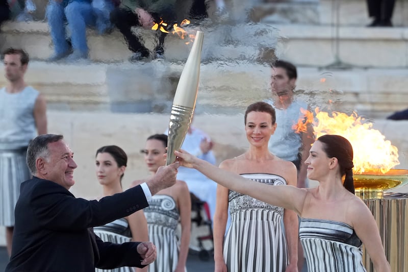 Actress Mary Mina, playing an ancient Greek high priestess, gives the torch with the Olympic flame to the head of Greece’s Olympic Committee, Spyros Capralos, at the Panathenaic Stadium in Athens (Petros Giannakouris/AP)