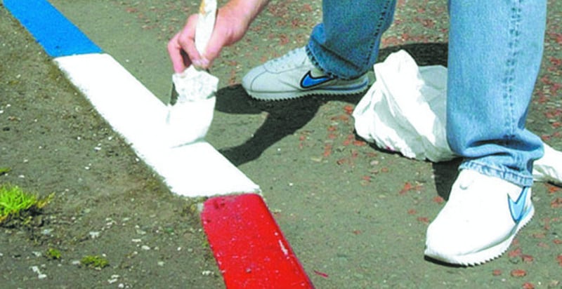 UFF leader Johnny Adair painting the kerb stones in the housing estate where he lives red white and blue on the lower Shankill Road file pic 
