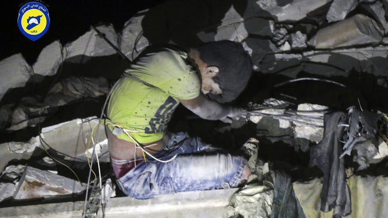 Rescue workers trying to remove a boy stuck in the debris of a building in the neighborhood of Qaterji in rebel-held east Aleppo following an airstrike in the Syrian city. Picture by Syrian Civil Defense White Helmets/Associated Press