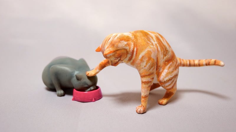 Two cats eating figurine