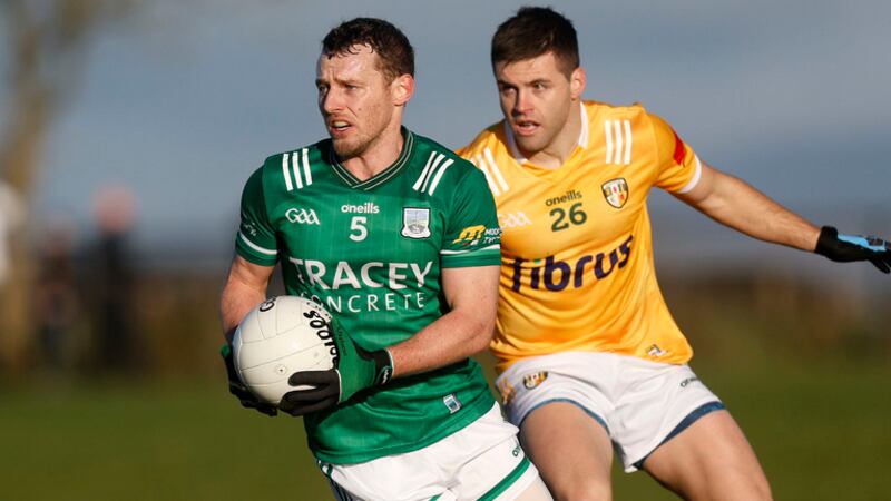 A Fermanagh GAA player runs away with the ball as he is pursued by an Antrim rival
