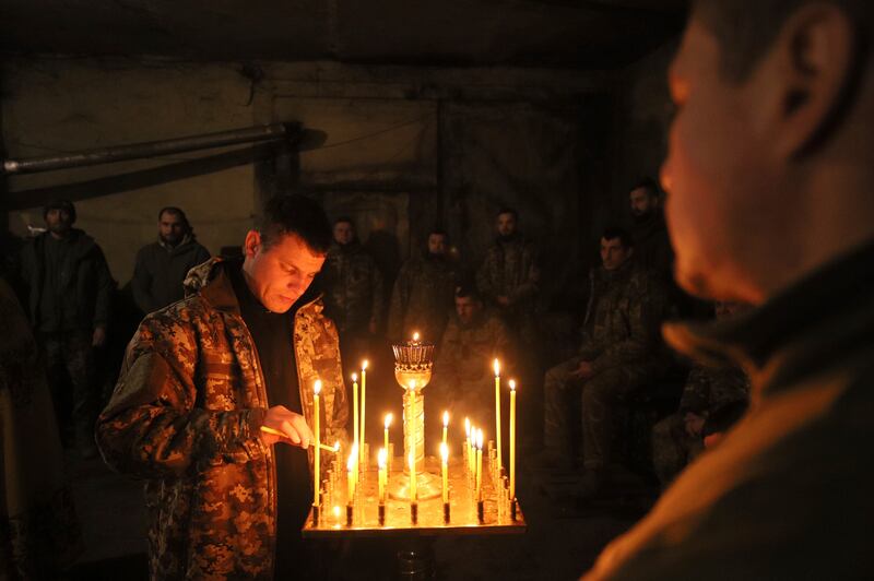 A Ukrainian serviceman of the 72nd mechanised brigade lights a candle during the sacred liturgy before the upcoming Christmas at the frontline near Vuhledar, Ukraine (Valentyn Kuzan/AP)