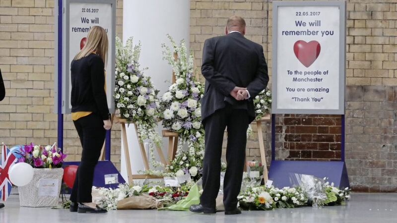 People look at floral tributes at Manchester Victoria railway station, which has reopened for the first time since the terror attack on the adjacent Manchester Arena PICTURE: Owen Humphreys/PA 