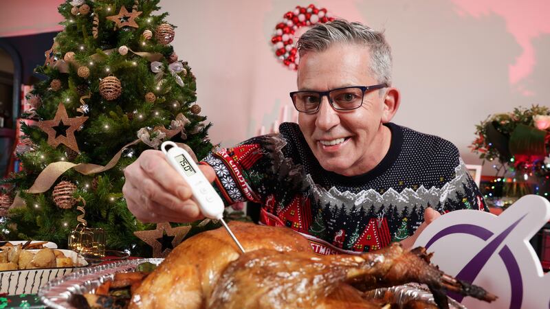 Chef Noel McMeel wearing a festive jumper whilst checking the temperature of his turkey.