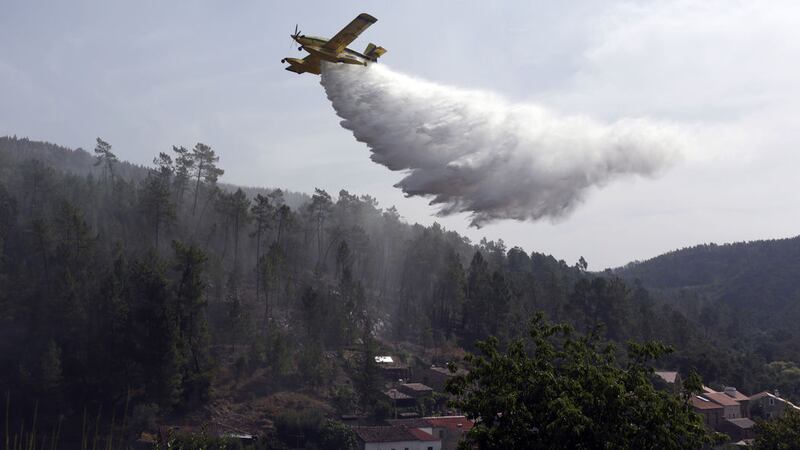 A firefighting plane drops its load to prevent wildfires from reigniting over the village of Agua Formosa, near Vila de Rei, central Portugal, yesterday. The small village was evacuated on Monday night when raging forest fires approached<br />Picture by Armando Franca/AP