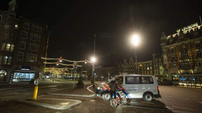 &nbsp;Police in Amsterdam check the papers of a woman who is out after curfew. Picture by Peter Dejong