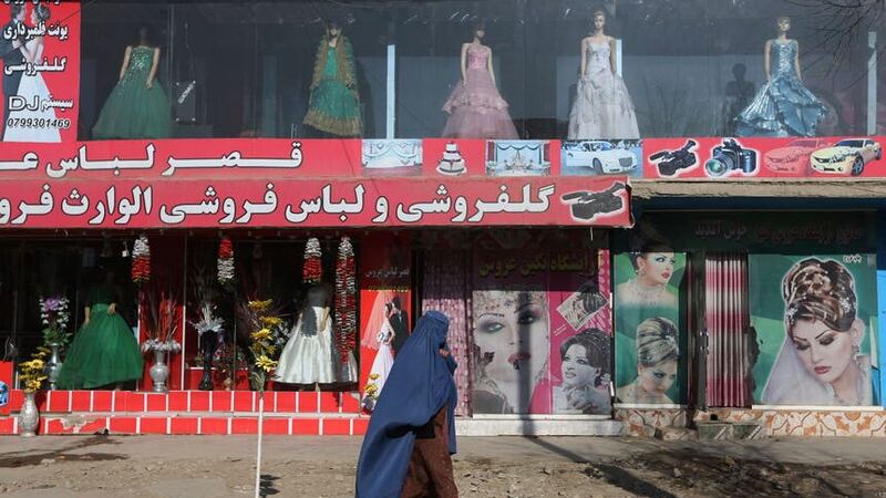 A woman walks past a beauty salon and dress shop in Kabul, Afghanistan. A spokesman at Afghanistan’s Vice and Virtue Ministry said the Taliban are banning women’s beauty salons (Rahmat Gul/AP/PA)