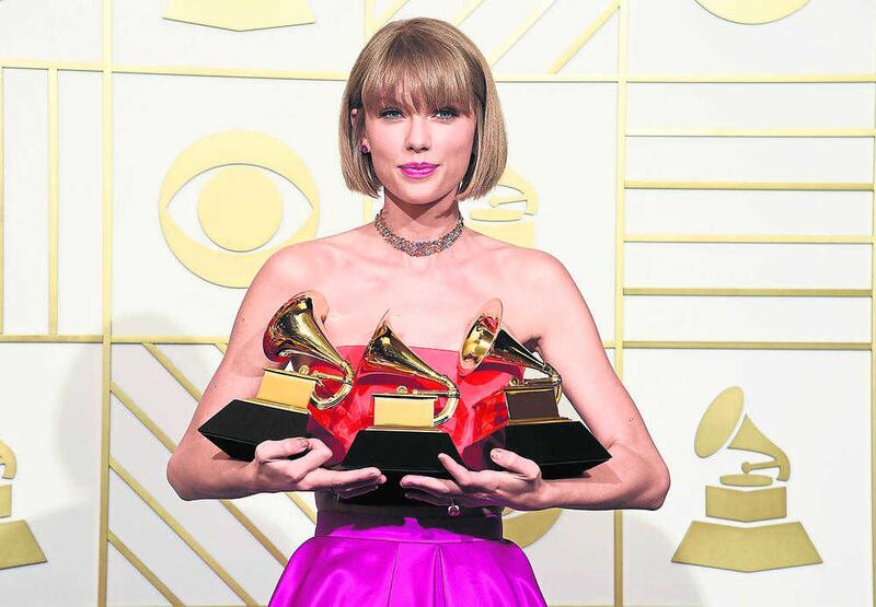 Taylor Swift poses in the press room with the awards for album of the year for 1989, pop vocal album for 1989 and best music video for "Bad Blood" at the 58th annual Grammy Awards at the Staples Center on Monday, Feb. 15, 2016, in Los Angeles. (Photo by Chris Pizzello/Invision/AP).