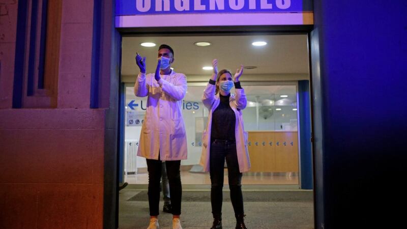 Health workers at the entrance to a hospital A&amp;E department react as people applaud from their houses in support of medical staff in Barcelona this week. Picture by Joan Mateu/AP 