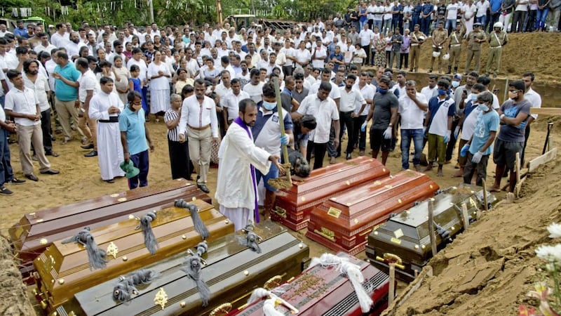 A priest conducts religious rituals during a mass burial for Easter Sunday bomb blast victims in Negombo, Sri Lanka, on Wednesday, April 24, 2019. Picture by Gemunu Amarasinghe, Associated Press 