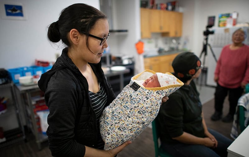 Tapia Tattuinee cradles her two-week-old daughter, Trudi, while attending a meeting for mothers in Rankin Inlet, Nunavut. Photo by Fred Lum.