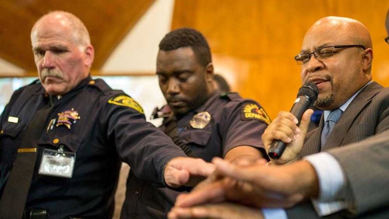 Dallas county sheriff assistant chief deputy Blaise Mikulewicz, left, joins hands with DeSoto mayor Carl O Sherman snr and another officer at meeting hosted by Dallas Area Interfaith at Southern Hills Church of Christ. Picture by Ting Shen, The Dallas Morning News/ Associated Press