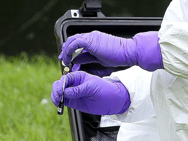 A forensic officer places a suspected bullet casing into an evidence bag at the scene of the paramilitary-style shooting. Picture by Mal McCann