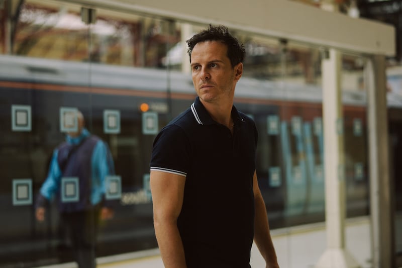 A scene from All of Us Strangers showing Andrew Scott as Adam at a train station