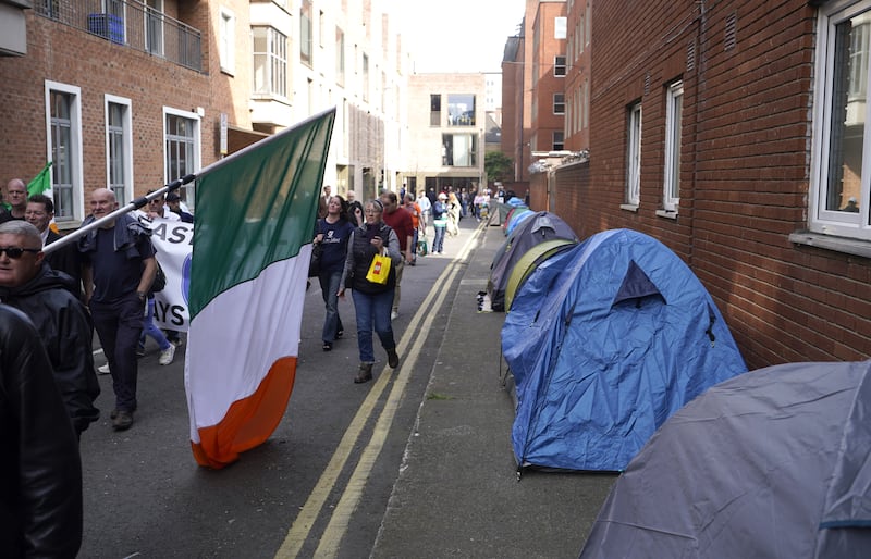 Protesters walk past tents of homeless people outside the International Protection Office in Dublin in May .