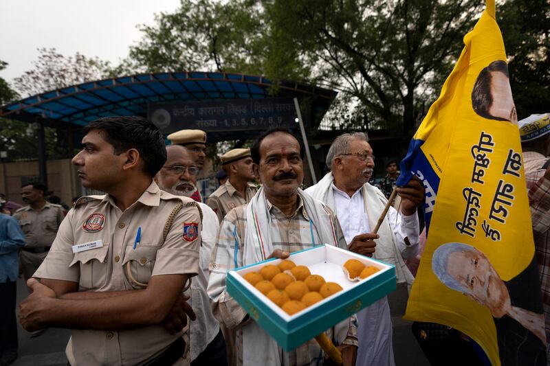 A supporter of the Aam Aadmi Party distributes sweets as he waits with others for the release of the party leader Arvind Kejriwal from Tihar Jail in New Delhi (Altaf Qadri/AP)