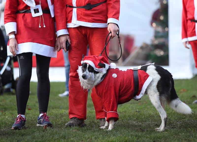Participants and their dog taking part in the London Santa Run in Victoria Park, east London