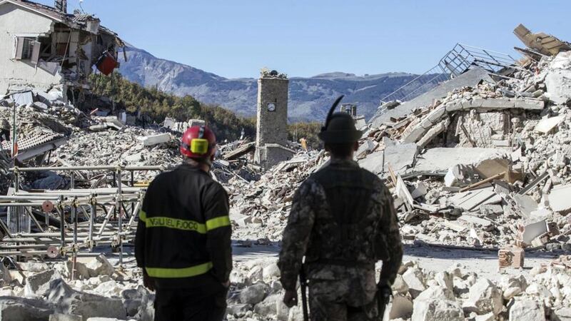 A firefighter, left, and an alpine soldier look at rubble caused by an earthquake in the hilltop town of Amatrice, Italy. Picture by Massimo Percossi, ANSA via Associated Press