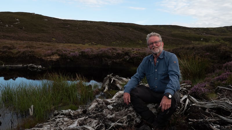 Cormac Ó hÁdhmaill sitting in a bog in Ireland and looking at the camera from a BBC press release