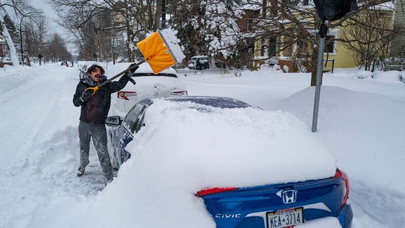 A Buffalo resident digs his car out of the snow (AP)