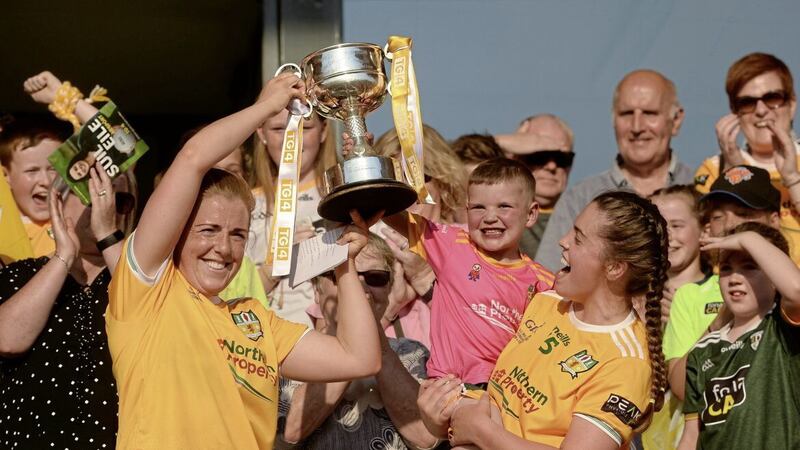 Antrim captain Cathy Carey, left, and Grainne McLaughlin lift the West County Hotel Cup along with four-year-old Daithi MacGabhann following the TG4 All-Ireland Ladies JFC Final replay win over Fermanagh. Photo by Oliver McVeigh/Sportsfile 
