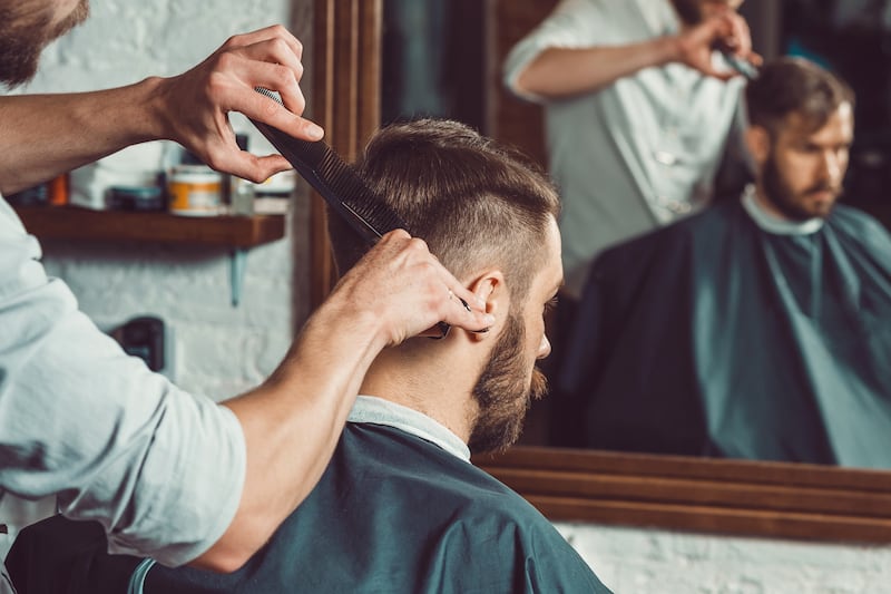 A man receives a haircut from a barber