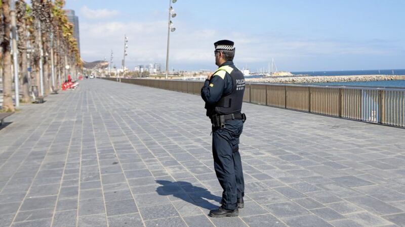 A police officer stands guard preventing access to the beach in Barcelona, Spain. Picture by AP Photo/Joan Mateu 