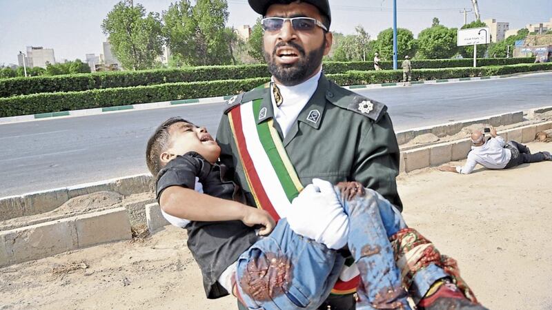 A Revolutionary Guard carries a wounded boy after a shooting during a military parade marking the 38th anniversary of Iraq's 1980 invasion of Iran, in the southwestern city of Ahvaz PICTURE: Behrad Ghasemi/ISNA via AP