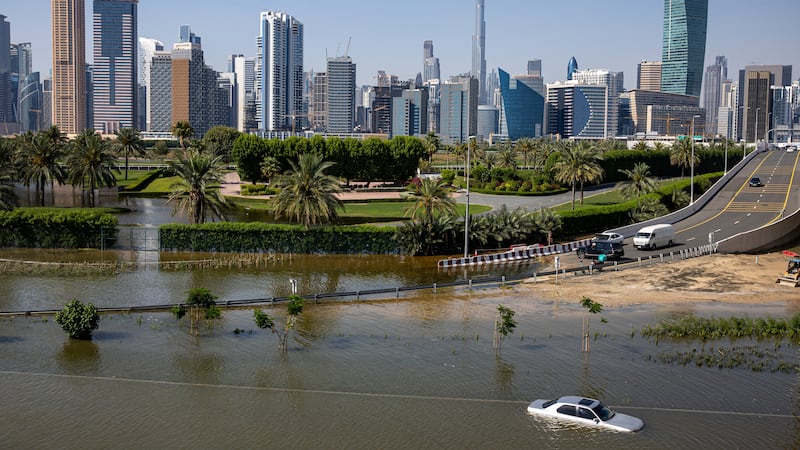 An abandoned vehicle stands in floodwater caused by heavy rain with the Burj Khalifa in the background (AP)