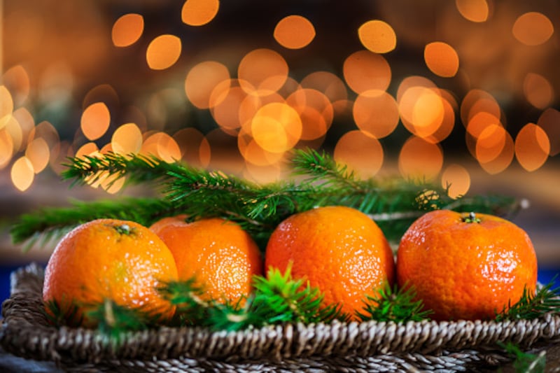Fresh Clementines or Tangerines, Xmas Lights and Xmas Tree Branch (gettyimages) 