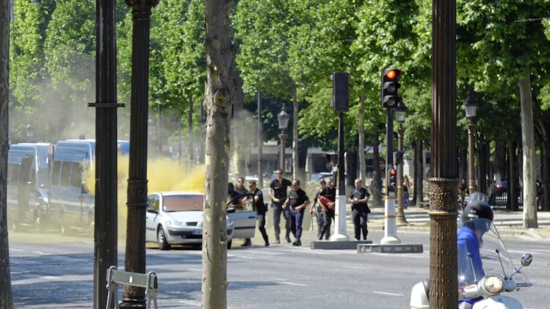 French gendarmes use fire extinguishers after a man rammed into a police convoy and detonated an explosive device on the Champs Elysees avenue in Paris, France, Monday. Picture by Noemie Pfister via Associated Press. 