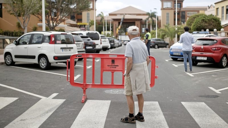 A bystander stands behind a security fence near the Costa Adeje Palace hotel on the Canary Island of Tenerife, which was placed in quarantine last month after an Italian doctor staying there tested positive for Covid-19 