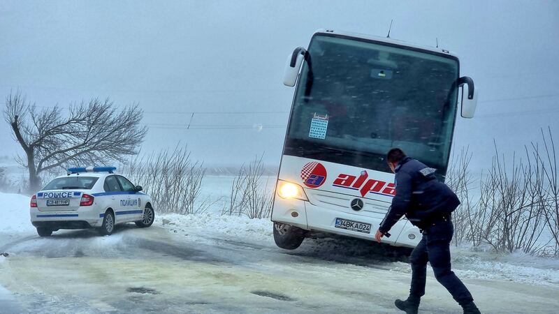 A policeman walks in front of a bus which went off the road near the town of Dobrich, Bulgaria (Bulgarian News Agency via AP)