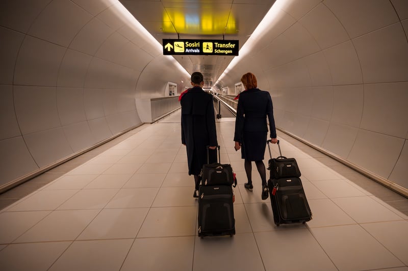 Flight attendants at Henri Coanda International Airport in Romania pass under a Schengen information sign (Andreea Alexandru/AP)
