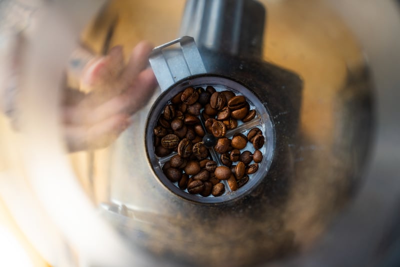 The fracturing and friction of coffee beans during grinding generates electricity that causes coffee particles to clump together and stick to the grinder