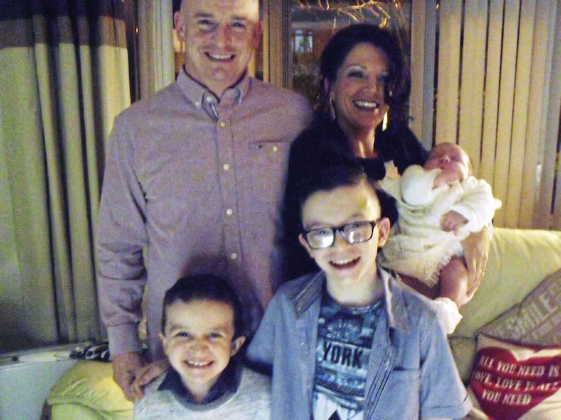 Sean McGrotty with his partner Louise holding their baby daughter alongside their sons Mark (12) and Evan, eight
