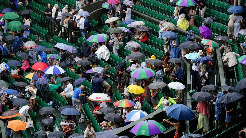 Spectators sheltering from the rain at Wimbledon on Saturday (Zac Goodwin/PA)