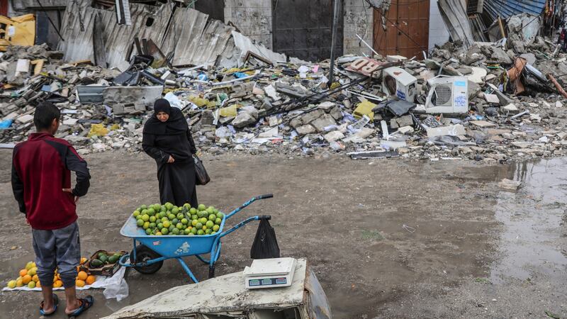 A Palestinian woman checks fruit in Gaza City which has been devastated by Israeli bombing (Mohammed Hajjar/AP)