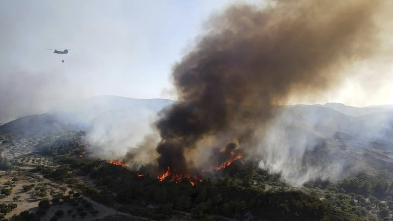 A military helicopter operates as flames burn a forest on the mountains near Vati village, on the Aegean Sea island of Rhodes