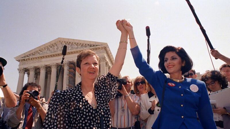 Norma McCorvey, Jane Roe in the 1973 court case, left, and her attorney Gloria Allred hold hands as they leave the Supreme Court building in Washington, April 26 1989, after sitting in while the court listened to arguments in a Missouri abortion case (AP Photo/J Scott Applewhite)