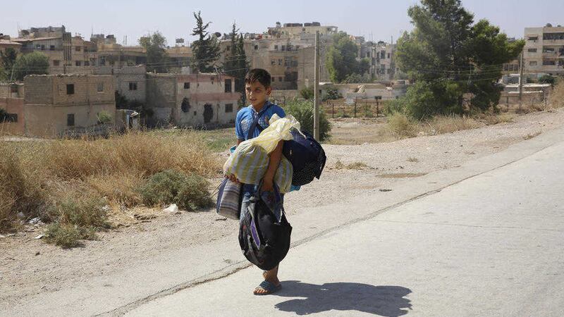 A boy carries his belongings as he leaves the Moadamiyeh suburb of Damascus, Syria. Picture by Associated Press, file 