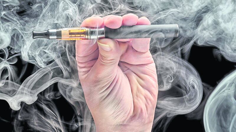 Hand holding an electronic cigarette over a dark background.