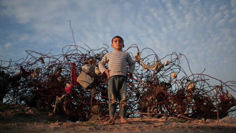 A Palestinian boy stands barefoot, next to remains of a destroyed house in the town of Beit Hanoun, northern Gaza Strip