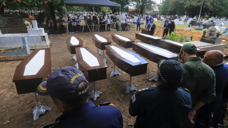 Authorities stand next to the nine coffins that contain the remains of unidentified migrants, at the Sao Jorge cemetery, in Belem, Para state, Brazil (Paulo Santos/AP)