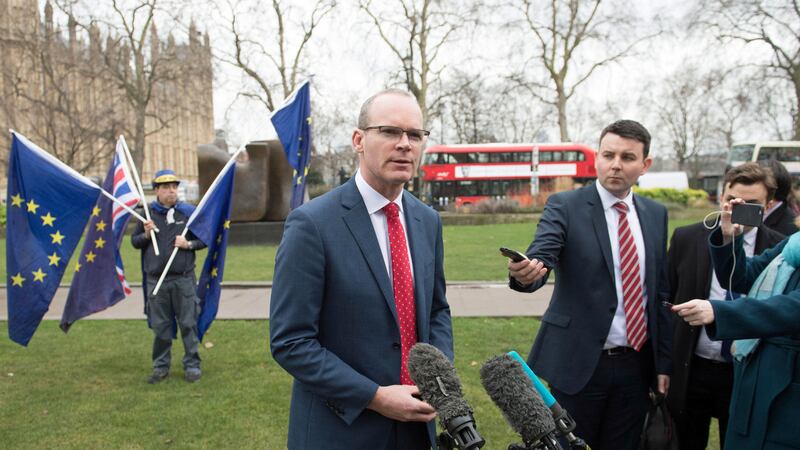 A man holding EU flags looks on (left) as Foreign Affairs Minister Simon Coveney speaks to the media on College Green in Westminster, London, after talks with newly appointed Secretary of State Karen Bradley&nbsp;