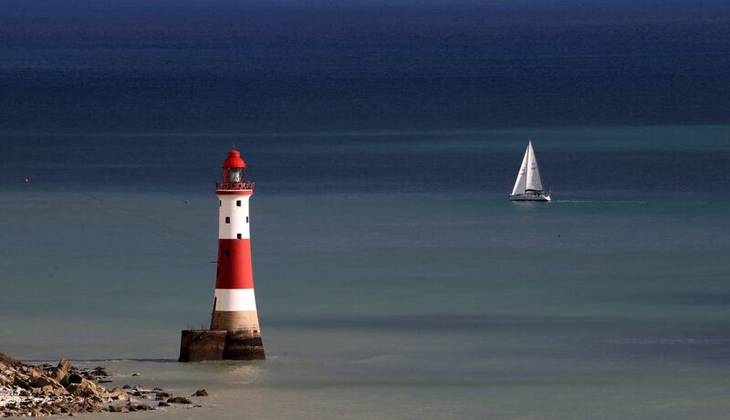 A yacht sails past Beachy Head lighthouse near Eastbourne in Sussex