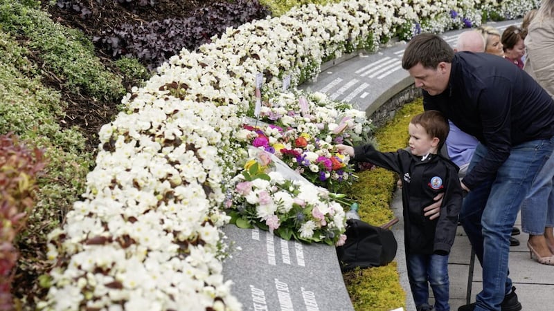 Gearoid Doherty, who lost his brother Oran in the 1998 Omagh bombing, lifts his son Daithi, aged 4, to place a flower during a service on Sunday to mark the 25th anniversary of the atrocity. Picture by Brian Lawless/PA Wire 